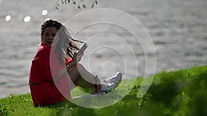 A surprised woman, thinking with a smartphone in her hand in the open air. Horny girl on the riverbank