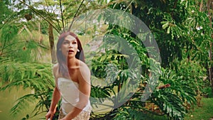 Surprised woman in a tropical garden looking over her shoulder