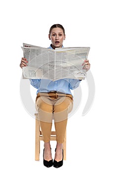 Surprised woman reading newspaper on white background