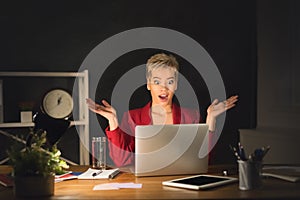 Surprised woman working on laptop late at night at office