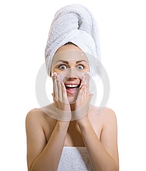 Surprised woman wrapped in a towel applaying cream or moisturiz