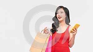 Surprised young Asian woman shopping online with smartphone and paying by credit card on white background