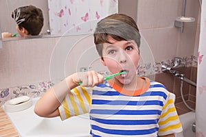 Surprised young boy cleaning his teeth in the bathroom