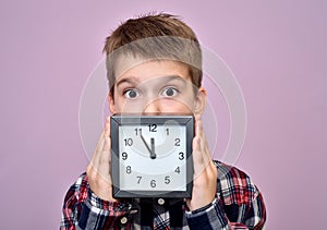 Surprised young boy with a clock