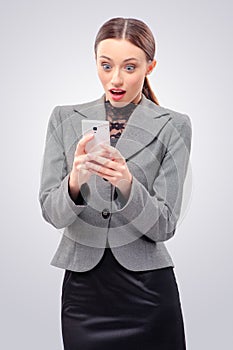 Surprised young business woman holding mobile phone