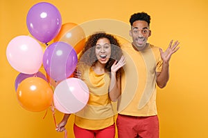 Surprised young friends couple african american guy girl in casual clothes isolated on yellow background. Birthday