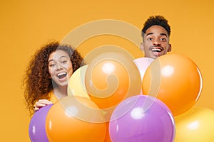 Surprised young friends couple african american guy girl in casual clothes isolated on yellow orange background