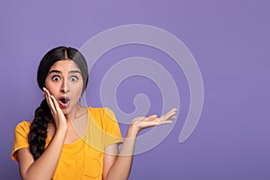 Surprised young indian woman showing copy space with palm