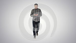 Surprised young man is holding phone and reading message on gradient background.