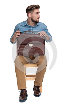 Surprised young man looking to side and holding suitcase