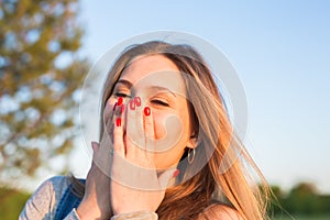 Surprised young woman covering her mouth with hands outdoors