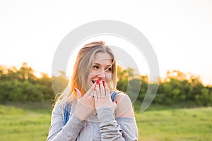 Surprised young woman covering her mouth with hands outdoors