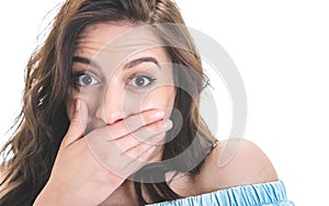 Surprised young woman covers her mouth keeps puppet eyes, isolated on white background. Astonished girl. Amazement concept