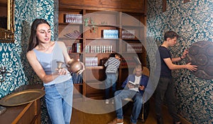 Surprised young woman examining ancient kettle in quest room