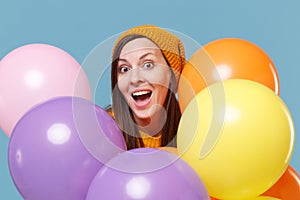 Surprised young woman girl in sweater hat posing isolated on blue background studio portrait. Birthday holiday party