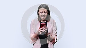 Surprised young woman looking in smartphone, white background