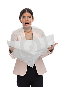 Surprised young woman in pink jacket reading newspaper