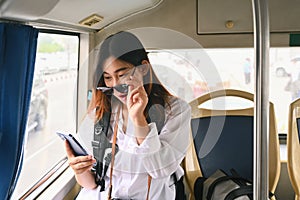 Surprised young woman reading message on her mobile phone while commuting by bus