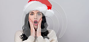 Surprised young woman in a Santa hat