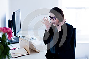 Surprised young woman sitting at the desk and looking at the tab