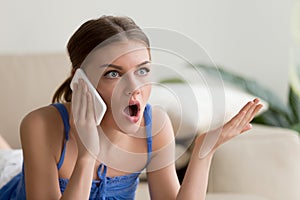 Surprised young woman talking on mobile phone