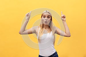 Surprised young woman wearing white clothes while looking at camera on yellow background.