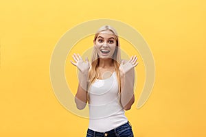 Surprised young woman wearing white clothes while looking at camera on yellow background.
