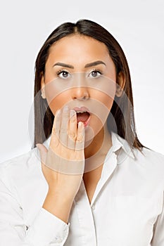 Surprised young woman with wide open eyes covering mouth with her hand