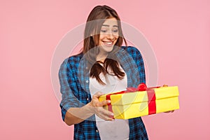 Surprising bonus, holiday present! Portrait of amazed happy girl in checkered shirt holding wrapped box photo