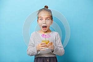 Surprized little girl with orange juice in hands.