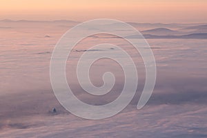 Surreal aerial view of Santa Maria degli Angeli church in Assisi, Italy, above a sea of fog at sunset