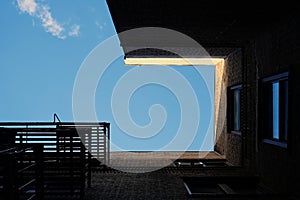 Surreal architectural abstraction of New York City tenement building framing blue sky