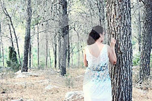 Surreal blurred background of young woman stands in forest. image is retro toned