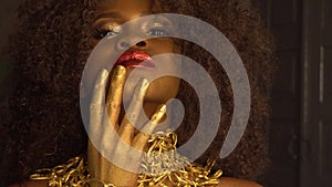 Surreal Fashion Portrait of African American Female Model with Golden Glossy Headwear. Creativity concept, black studio