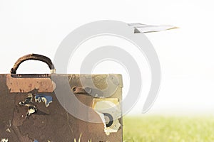 Surreal image of a paper airplane flying over a suitcase