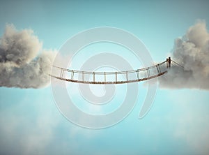 Surreal image of a rope bridge connecting two clouds