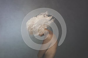 Surreal image of a white cloud covering a woman`s face, concept of freedom