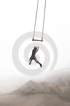 Surreal jump of a boy trying to hang himself in a swing that twirls in the sky, concept of risk and success