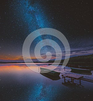 Surreal lake with boats under starry sky