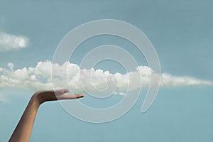 Surreal moment between a cloud and a hand of a person