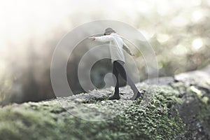 Surreal moment of a woman walking balanced on a giant tree trunk in the forest