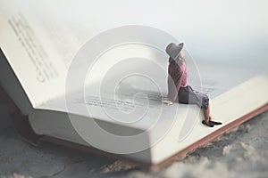 Surreal moment of a woman relaxes sitting on a giant book photo
