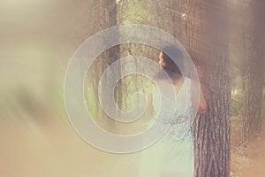Surreal photo of young woman standing in forest. image is textured and toned. dreamy concept