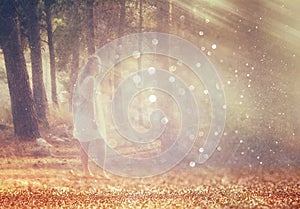 Surreal photo of young woman standing in forest. image is textured and toned. dreamy concept