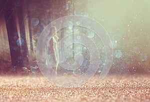 Surreal photo of young woman standing in forest. image is textured and toned. dreamy concept.