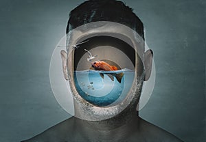 Surreal portrait of man with cropped face filled with water with a fish inside on a blue background. Surreal image. Surrealism