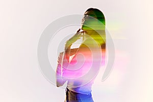 Surreal portrait of young adorable woman posing over white background with mixed neon colored light on her body. Concept