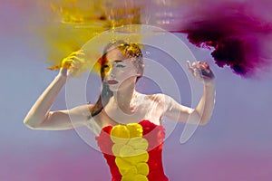 Surreal portrait of young attractive woman with air bubbles underwater in colorful water with ink