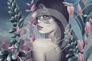 Surreal portrait of young woman with lace mask in fantasy garden