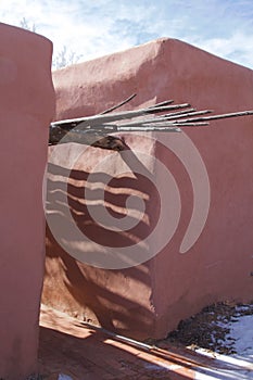 Surreal shadows cast on an Adobe building by sun streaming through vigas